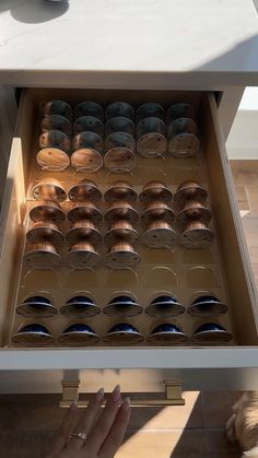 a drawer full of empty plates and bowls in someone's hand on the floor