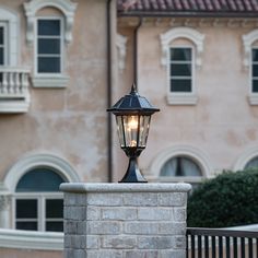 an old fashioned street light on top of a brick wall in front of a building