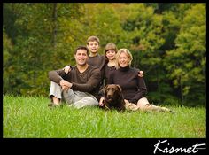 a family sitting in the grass with their dog