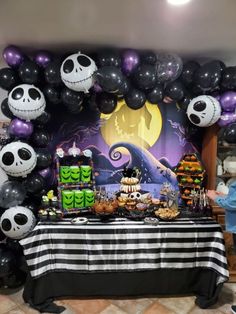 the table is decorated with black and white balloons, skulls, and other halloween decorations