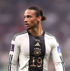 the soccer player is wearing a black and white uniform with gold numbers on his shirt