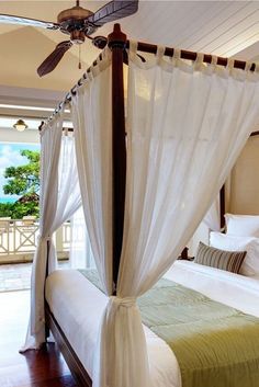 a canopy bed with white drapes and pillows