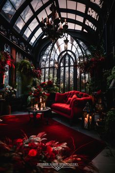 a living room filled with red furniture and lots of greenery on the walls next to a chandelier