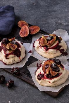 three pastries are sitting on top of some parchment paper and topped with berries, figs and plums pavoa