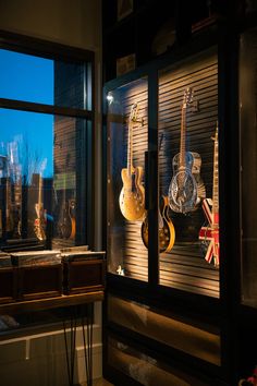 guitars and other musical instruments are on display in a shop window at night, with the british flag visible behind them