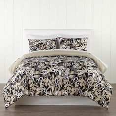 a bed covered in black and white comforter next to a wooden floor with two lamps on it