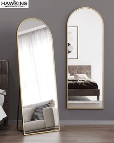 a large mirror sitting on top of a wooden floor next to a bed in a bedroom