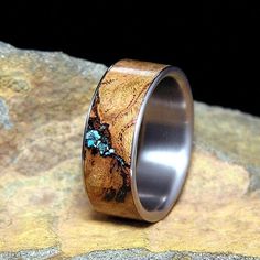 a wooden ring with blue flowers inlayed to it's surface on top of a rock