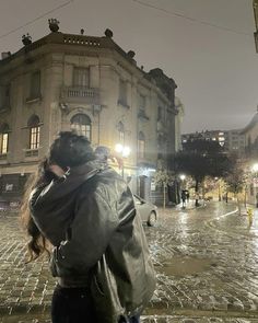 a woman walking down a street at night with her back to the camera, holding an umbrella