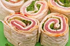 there are many rolls that have meat and vegetables in them on the green tablecloth