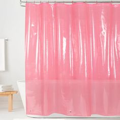 a pink shower curtain in a bathroom next to a white bath tub and toilet paper