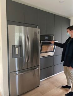 a woman wearing a face mask standing in front of an oven with the door open