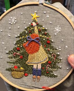 a hand embroidered christmas tree with a girl holding a basket in it's hands