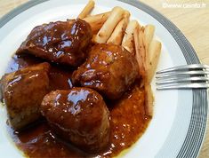 a white plate topped with meat covered in gravy next to french fries and ketchup