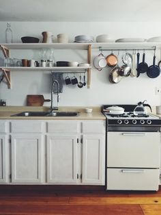 a white stove top oven sitting inside of a kitchen next to a wooden countertop