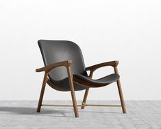 a grey chair with wooden legs and arm rests against a white wall in an empty room