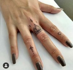 a woman's hand with tattoos on it and an arrow tattooed on the middle finger