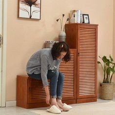 a woman sitting on top of a wooden cabinet