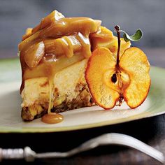 a piece of cheesecake with caramel sauce and sliced apples on a plate next to a fork