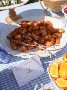 a table topped with plates of food and oranges next to a basket of fruit