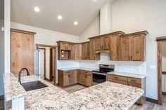 an empty kitchen with granite counter tops and wooden cabinets