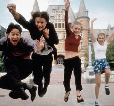 four people jumping in the air with their hands up and one person holding his arms out