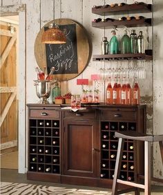 a wine bar with lots of bottles and glasses on the top shelf next to a chair