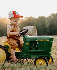 a toddler sitting on top of a green tractor