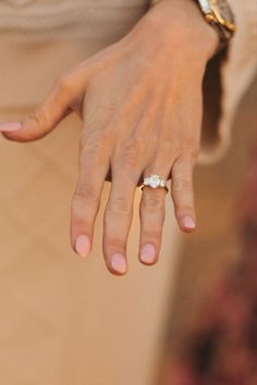 a close up of a person's hand with a diamond ring on their finger