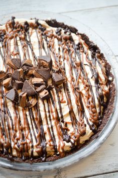 a pie with chocolate, cream and peanut butter on top sitting on a wooden table