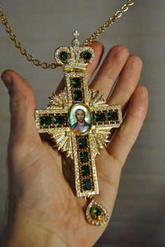 a person holding a cross with green and white stones