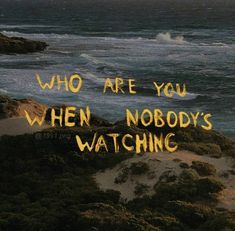 the words who are you when nobody's watching written in yellow on top of sand dunes