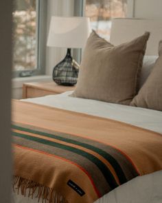 a bed with pillows and blankets on top of it in front of a large window