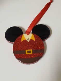 a mickey mouse ornament with a red ribbon on it's head and ears