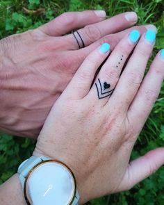 two people holding hands with tattoos on their fingers