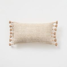 a beige pillow with tassels on the front and back, against a white background