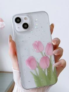 a woman holding up a phone case with pink flowers on it