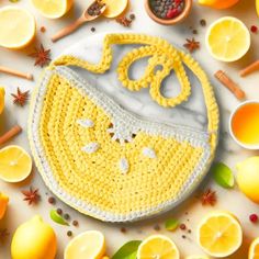 a crocheted lemon purse surrounded by sliced lemons and other citrus fruits on a white surface