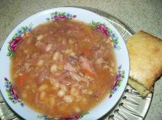 a white plate topped with soup next to a piece of bread