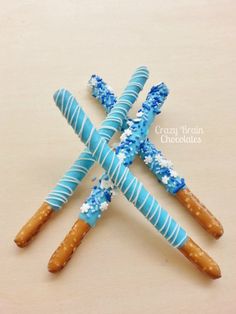 three blue and white pretzels with sprinkles on them are arranged in the shape of crosses