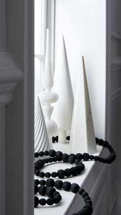 some white vases and black beads on a window sill