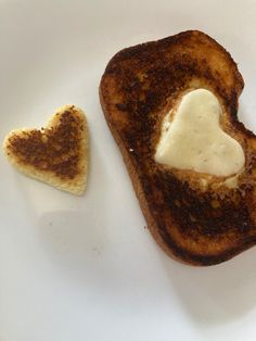 two pieces of toast on a plate with butter in the shape of a heart and a piece of bread shaped like a heart