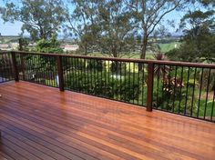 a wooden deck with metal railings and trees in the background