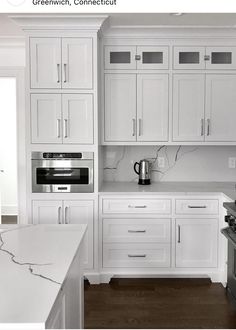 a kitchen with white cabinets and stainless steel appliances