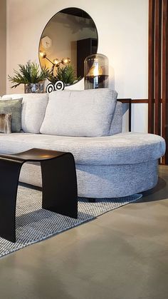 a white couch sitting on top of a rug in a living room next to a mirror