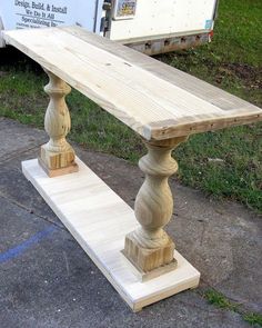 a wooden bench sitting on the side of a road next to a white box truck