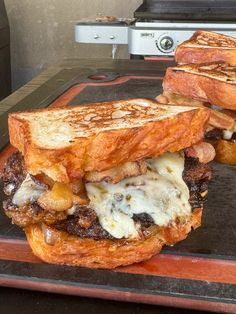 two toasted sandwiches sitting on top of a pan with meat and cheese in them