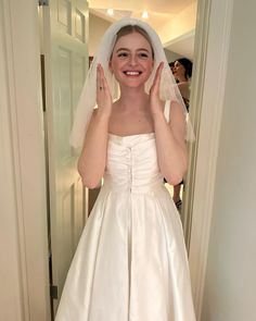 a woman in a white wedding dress is posing for the camera with her hands on her face