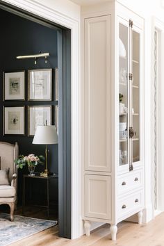 a white armoire sitting in the middle of a living room next to a chair