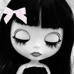 a close up of a doll with long black hair and pink bows on her head